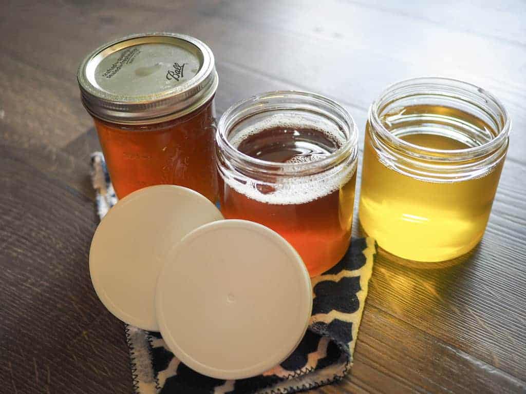 Three glass jars full of homemade clarified butter, two lids are open.