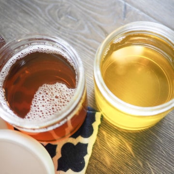 Three glass jars full of homemade clarified butter, two lids are open.