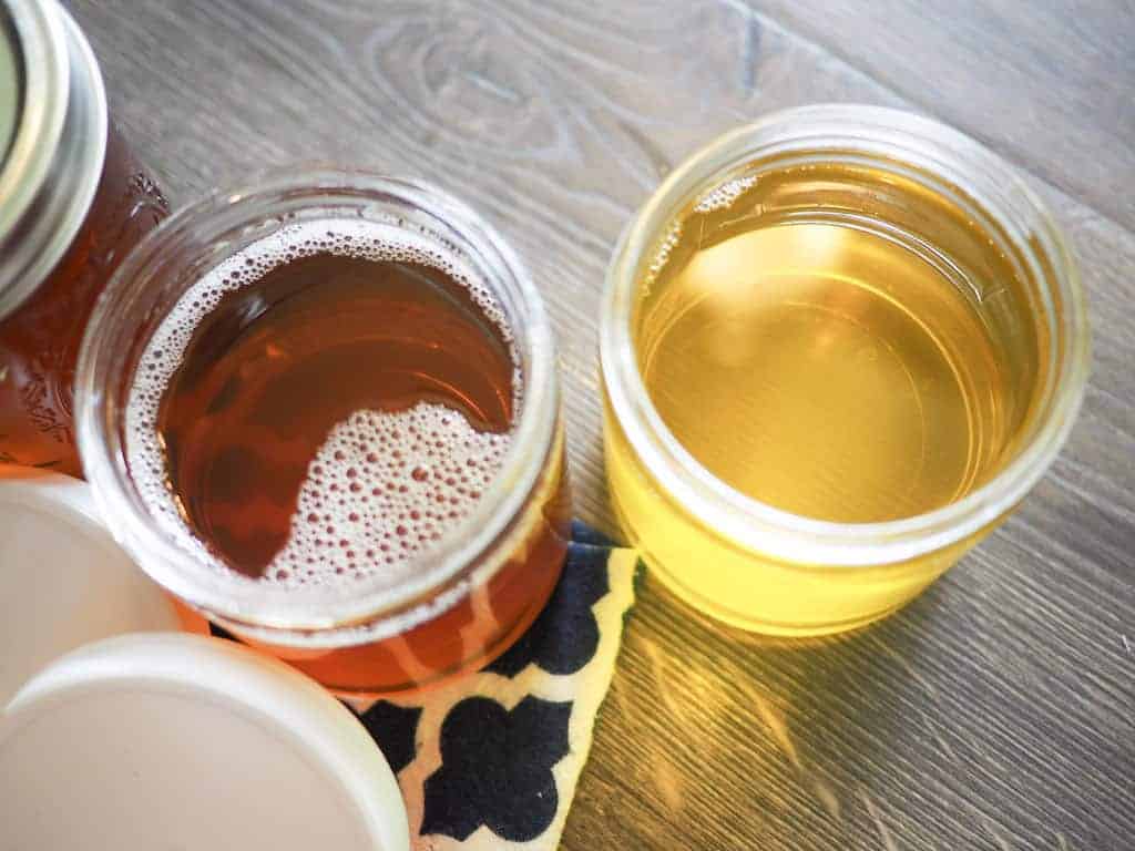 Three glass jars full of homemade clarified butter, two lids are open.