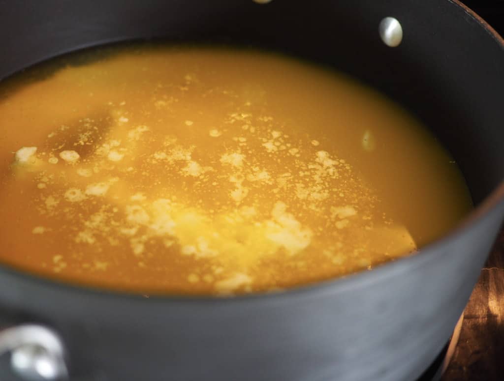 A large black saucepan filled with golden melted butter.