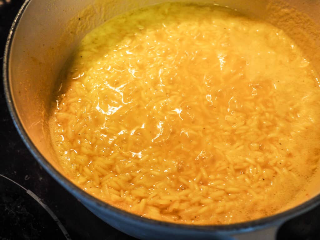Rice pilaf simmering in a white and gray pot.