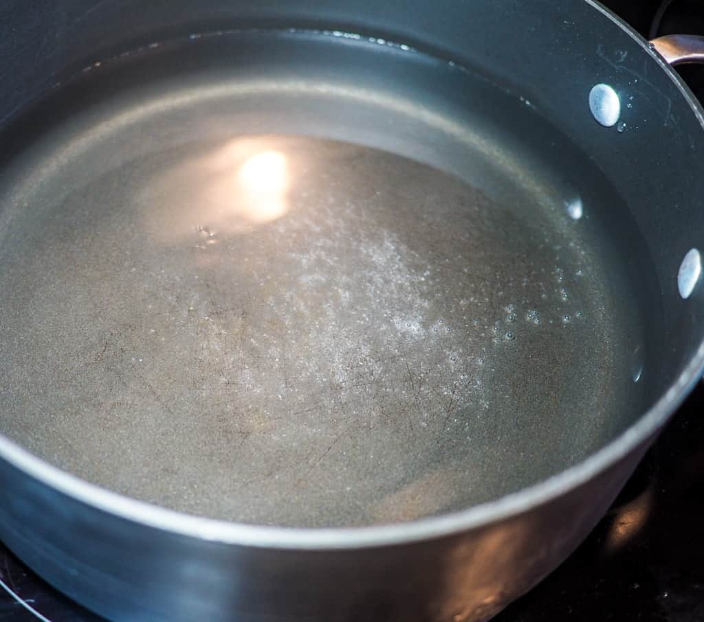 A black pot with water and salt, just beginning to boil.
