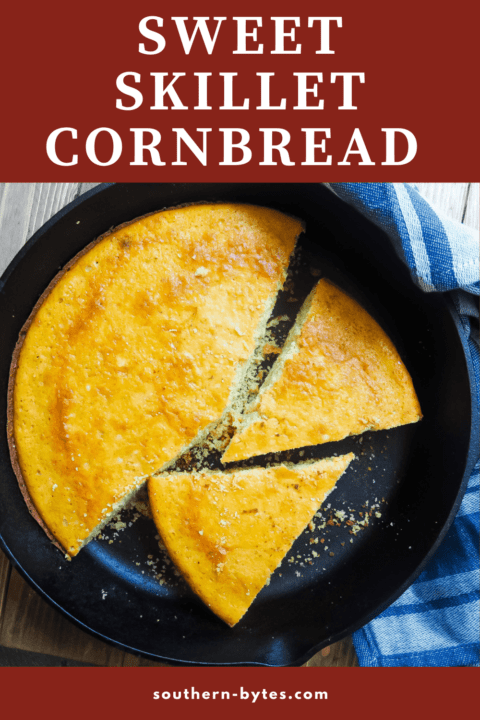 Cornbread in a cast iron skillet with a red and white dish towel on a gray wood background.