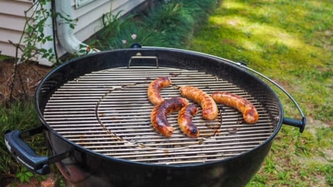 Green onion sausage on a round charcoal grill.
