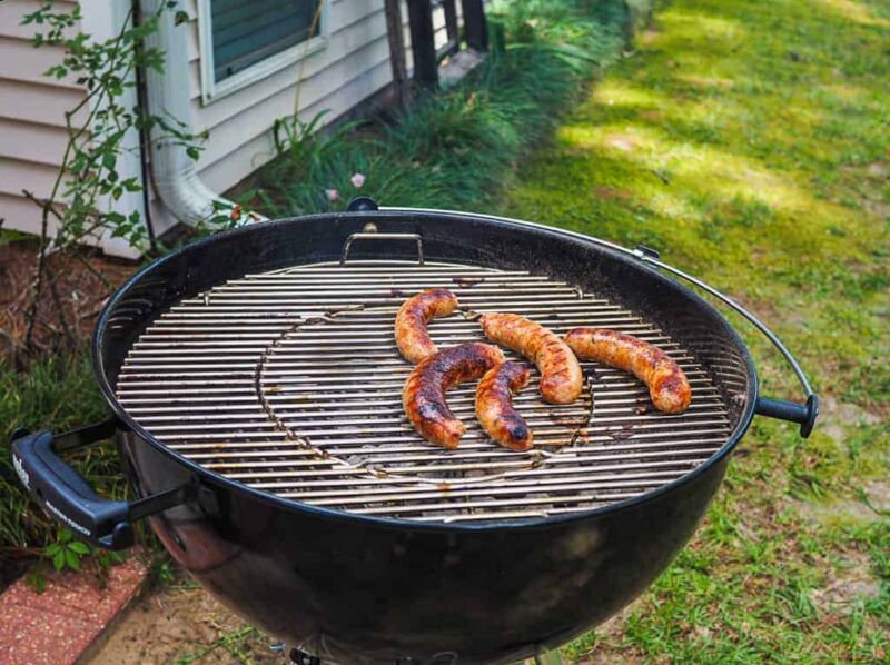 Green onion sausage on a round charcoal grill.