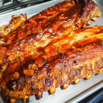 Cooked baby back ribs on a silver pan.