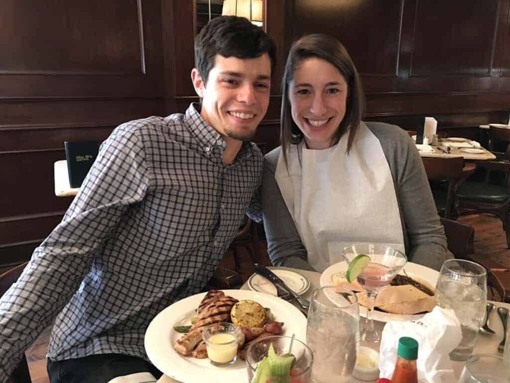 A brown haired man and a brown haired woman at a table in Mr. B's Bistro in New Orleans. The woman is wearing a bib to eat barbecue shrimp.