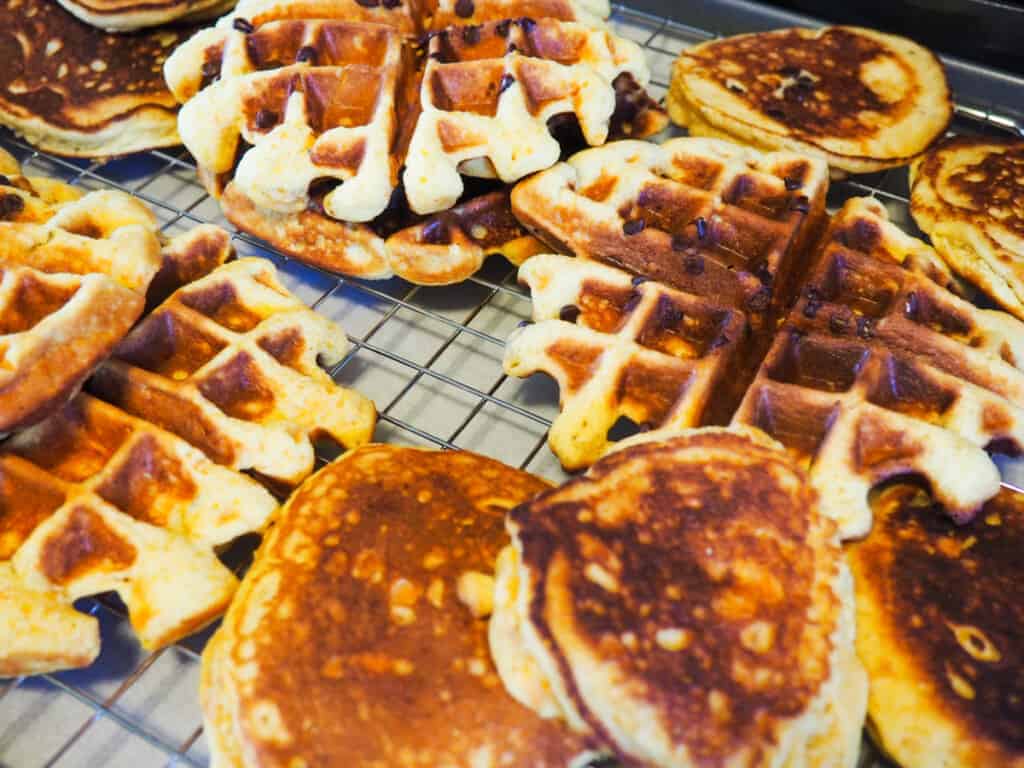 A wire rack in an oven covered with pancakes and waffles.