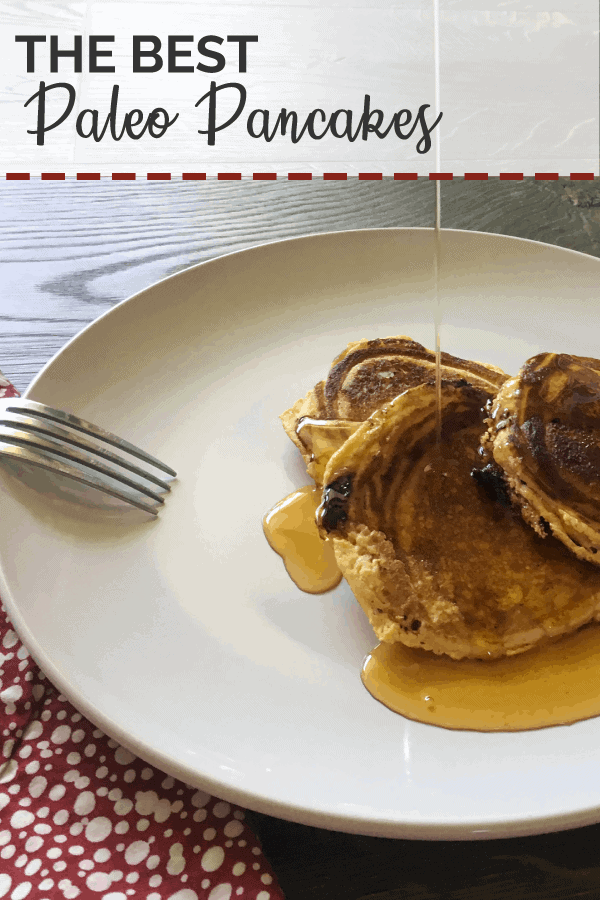 A white plate with three paleo pancakes and a red napkin with a drizzle of maple syrup.