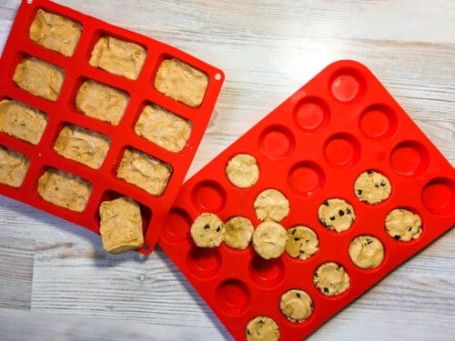 Two red silicon baking mats - one filled with rectangular peanut butter perfect bars and one filled with mini-muffin sized peanut butter perfect bars and peanut butter and chocolate chip perfect bars.