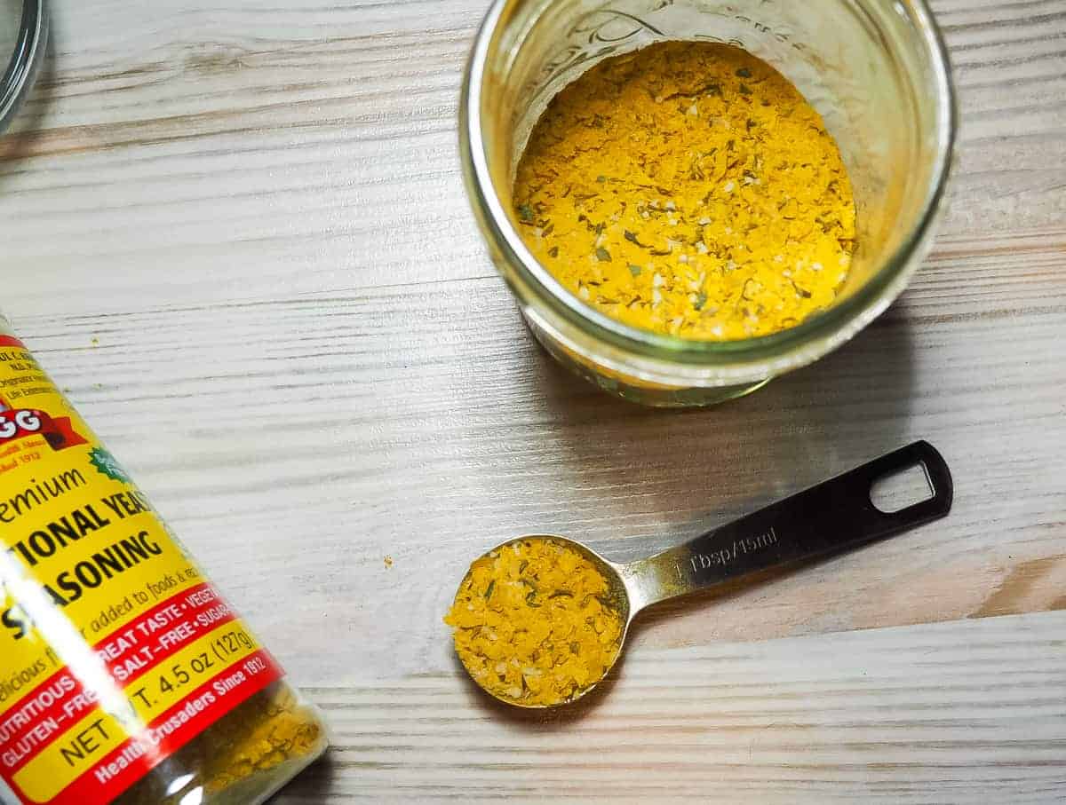 A jar of mixed homemade chicken bouillon with a spoon full of bouillon.