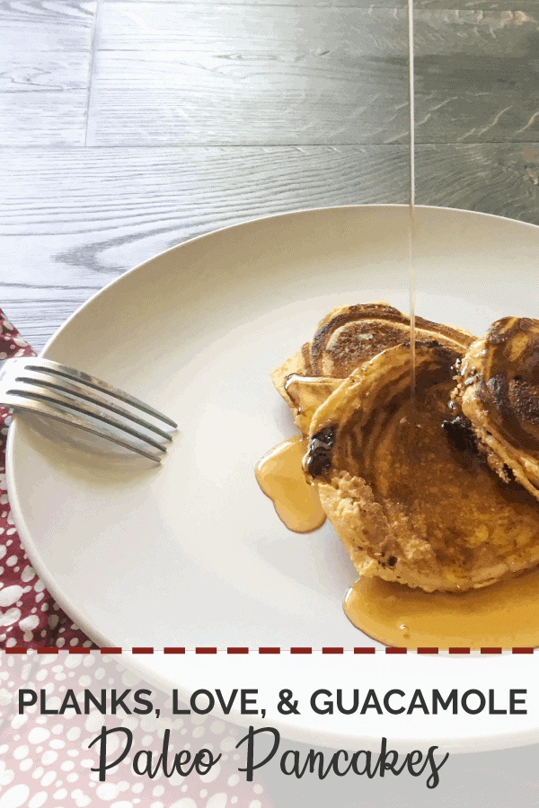 Three chocolate chip paleo pancakes on a white dish being drizzled with maple syrup.