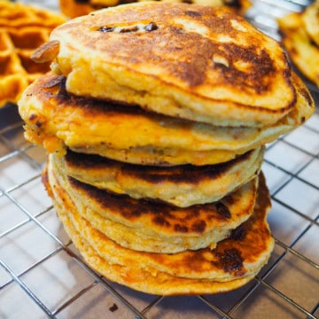 A stack of paleo sweet potato pancakes and waffles on a cooling rack.