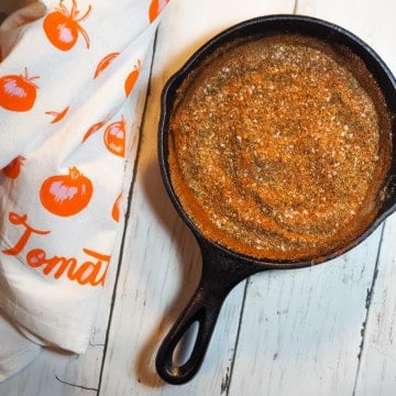 A small cast iron pan with the mixed ingredients of cajun seasoning mix in it.