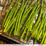 A pin image of a sheet pan covered in foil with oven roasted asparagus.