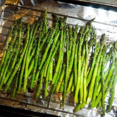 A sheet pan covered in foil with oven roasted asparagus.