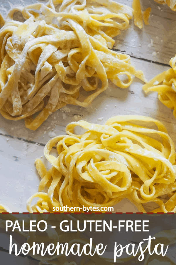 A pin image of piles of homemade paleo pasta on a white wooden board.