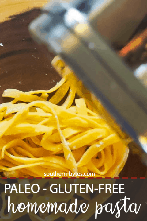 A pin image of pile of pasta coming out of a pasta maker on a wood cutting board.
