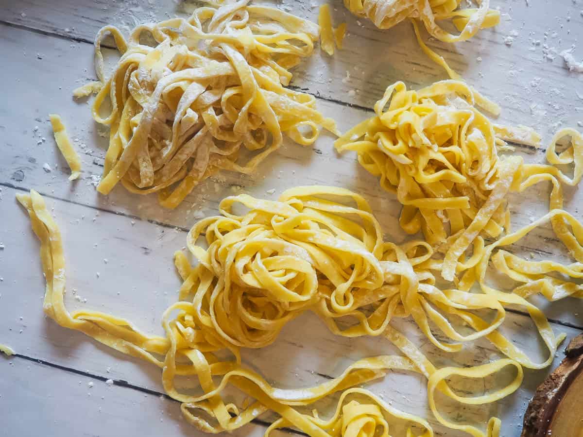 Piles of homemade paleo pasta on a white wooden board.