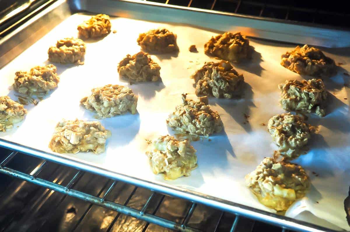 A cookie sheet covered in peanut butter dog treats in the oven.