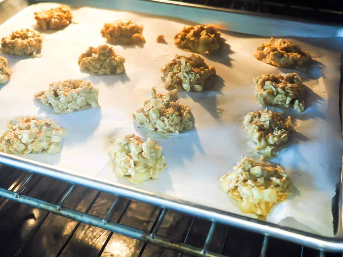 A cookie sheet covered in peanut butter dog treats in the oven.