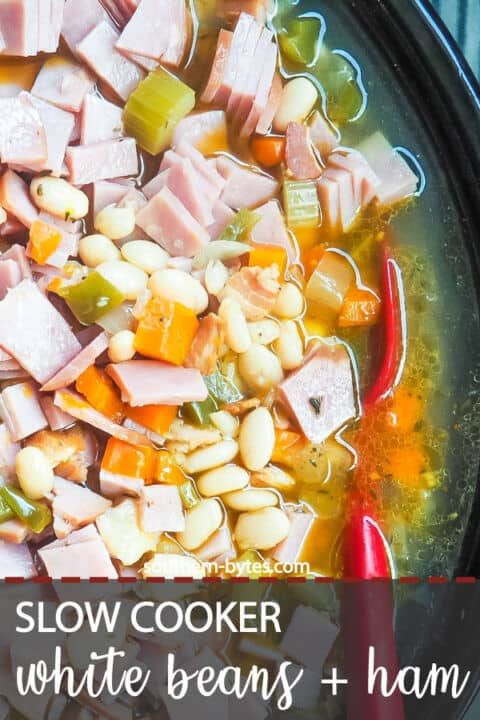 A pin image of a crockpot filled with white beans and ham, cooking.