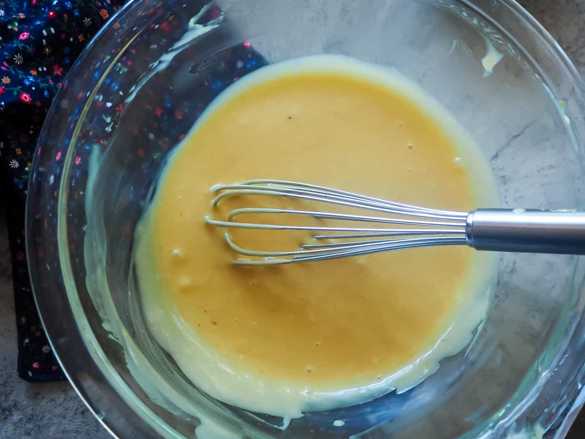 A clear bowl with the ingredients for copycat chick-fil-a sauce with a whisk, mixed.