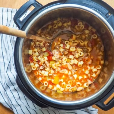 A instant pot of pasta e fagioli with a ladle scooping some out.