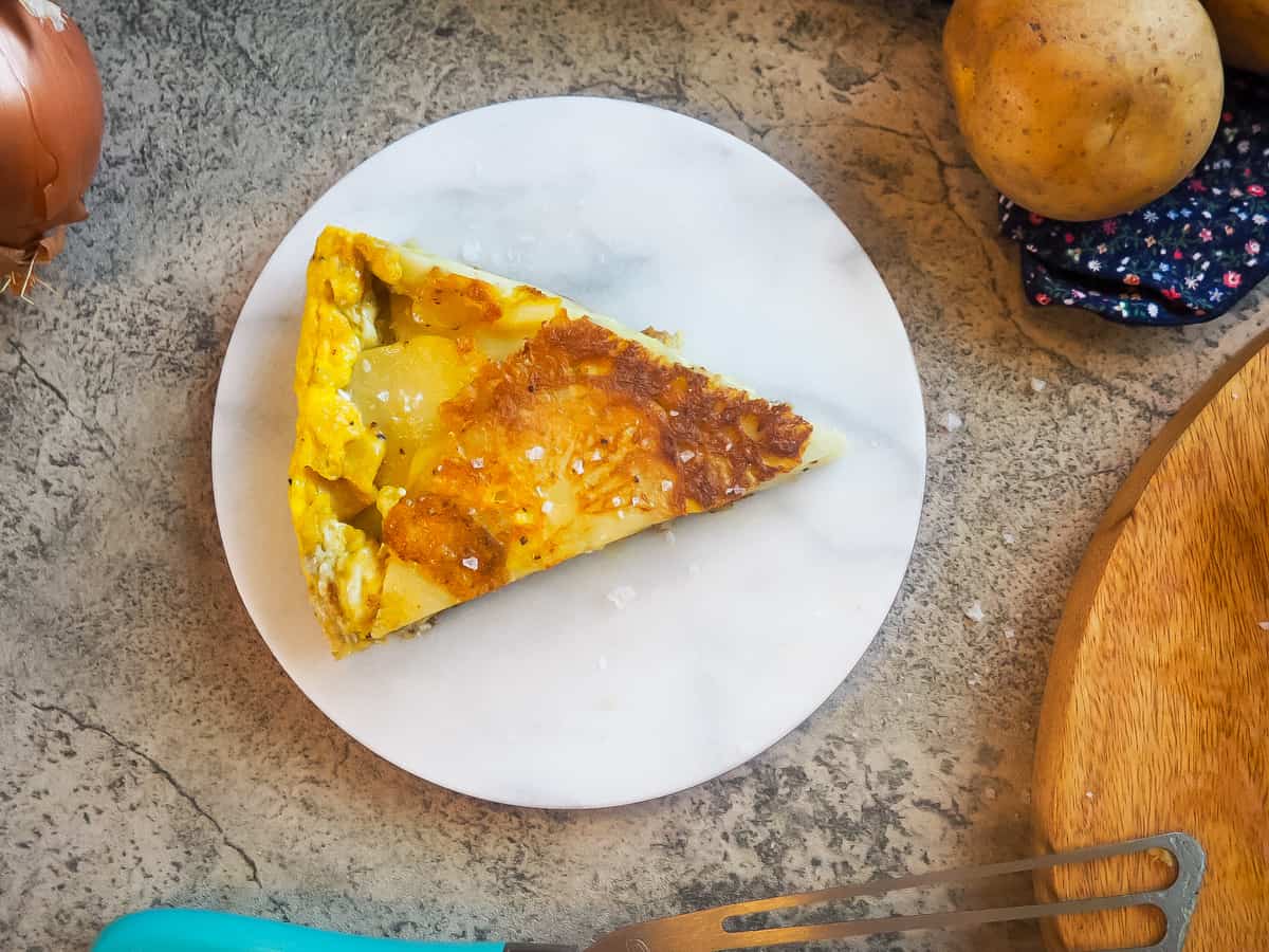 A slice of Spanish tortilla on a marble plate.