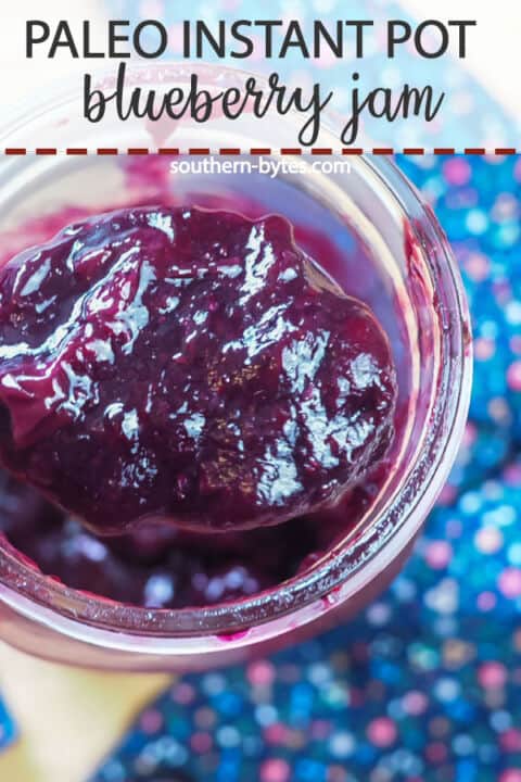 A pin image of a spoon scooping paleo blueberry jam out of a large jar.