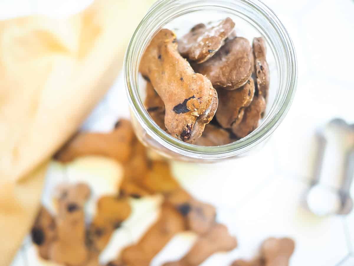 A pile of crunchy blueberry dog treats and a mason jar filled with treats on a tile background.