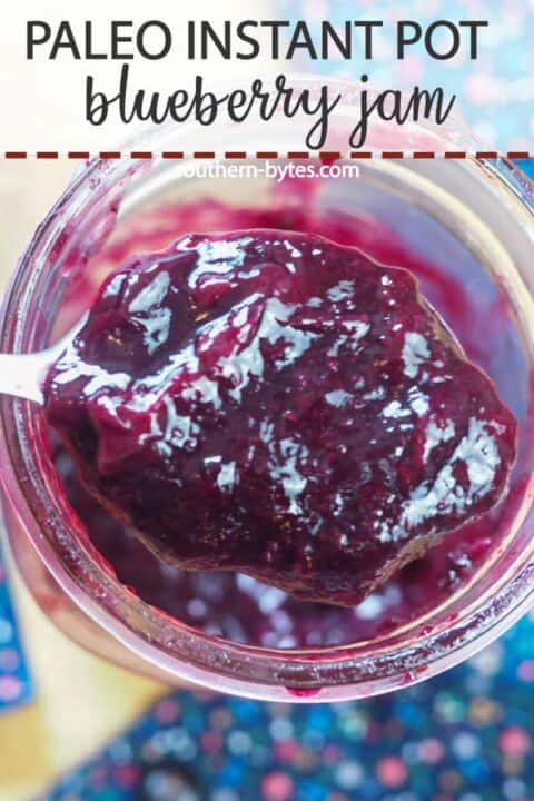 A pin image of a spoon of blueberry jam in a large jar.