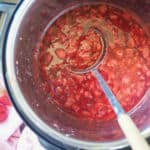 An overhead image of a spoon scooping paleo strawberry jam out of an Instant Pot.