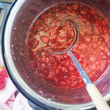 An overhead image of a spoon scooping paleo strawberry jam out of an Instant Pot.