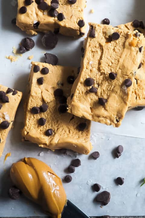 Peanut butter and chocolate chip perfect bars on a piece of parchment paper with a knife and a glob of peanut butter.