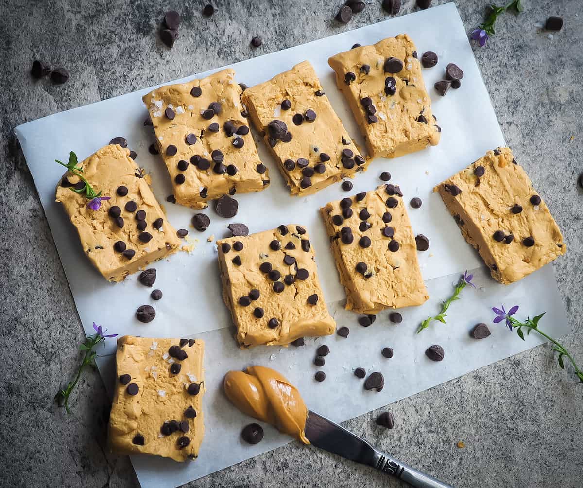 Peanut butter and chocolate chip perfect bars on a piece of parchment paper with a knife and a glob of peanut butter.