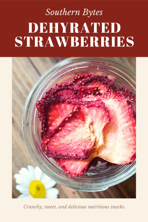 A pin image of a jar of dehydrated strawberries on a wood background with some daisies scattered around.