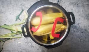 an instant pot with cooked steaming corn in it