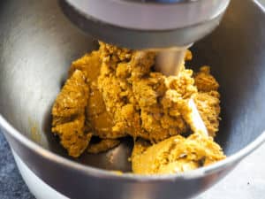 a stand mixer with orange dog treat batter in it