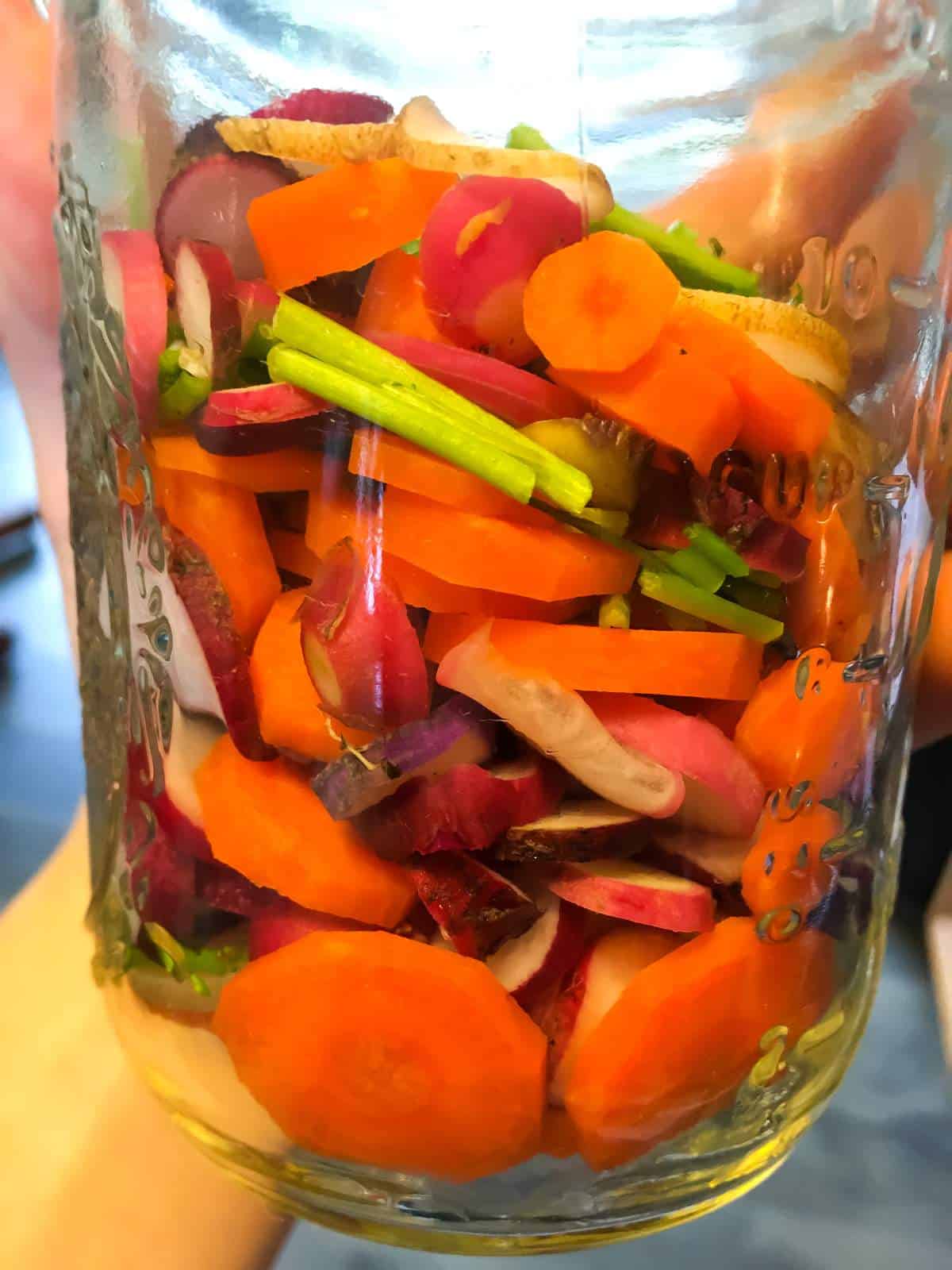 a jar of sliced carrots and radishes