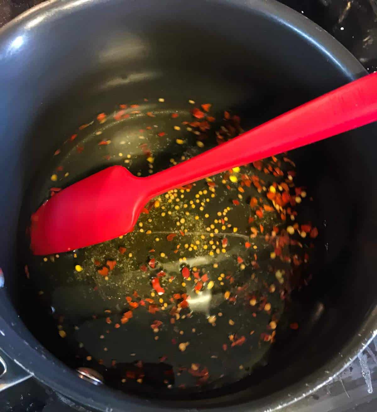 pickling brine cooking in a black pot with a red spatula