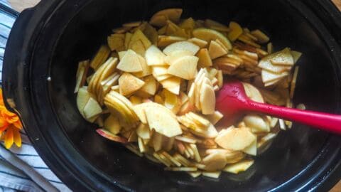 a crockpot with apples coated in cinnamon and maple in it.