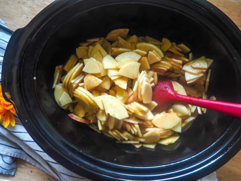 a crockpot with apples coated in cinnamon and maple in it.