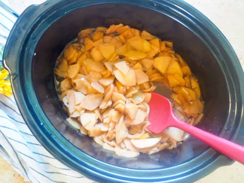 a crockpot with cooked apples coated in cinnamon in it.