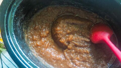 A crockpot with cooked apple butter in it.