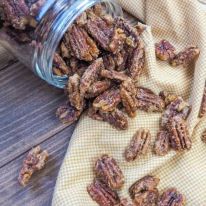 a spilled jar of candied pecans on a white and yellow napkin.
