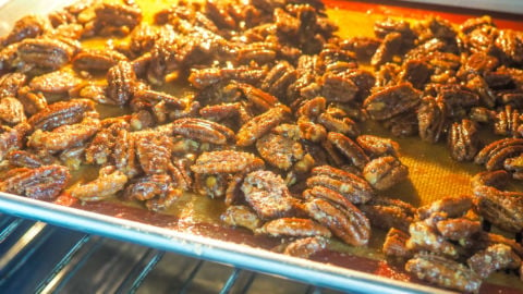 a tray of candied pecans baking in the oven.