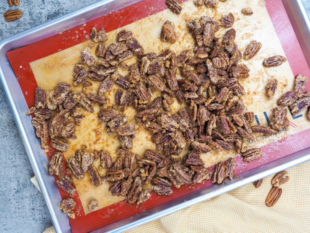 a baking sheet with cooked candied pecans on it.