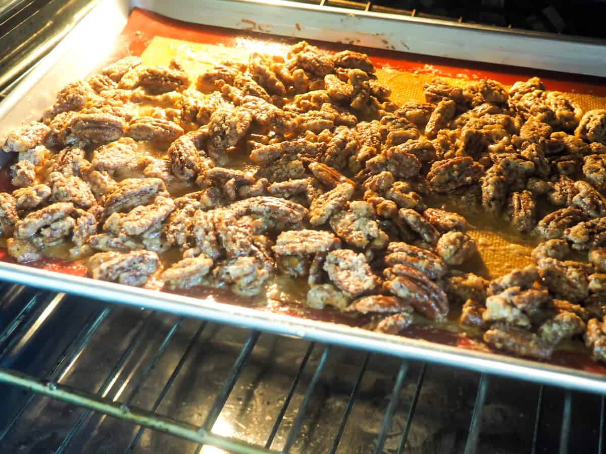 a tray of candied pecans baking in the oven.