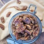a jar of candied pecans and a yellow and white plaid napkin.
